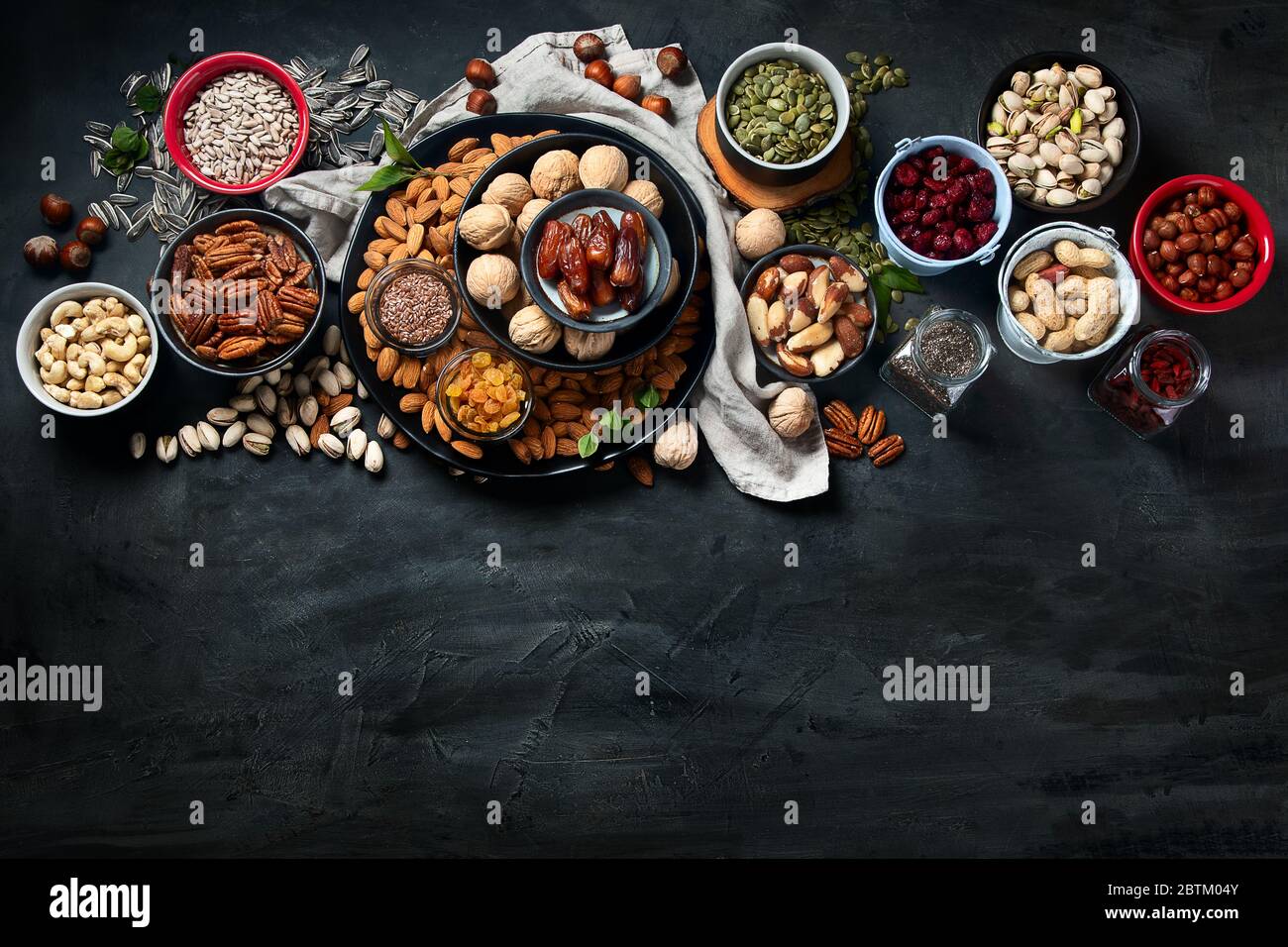 Different types of nuts, seeds and dried fruits on black background