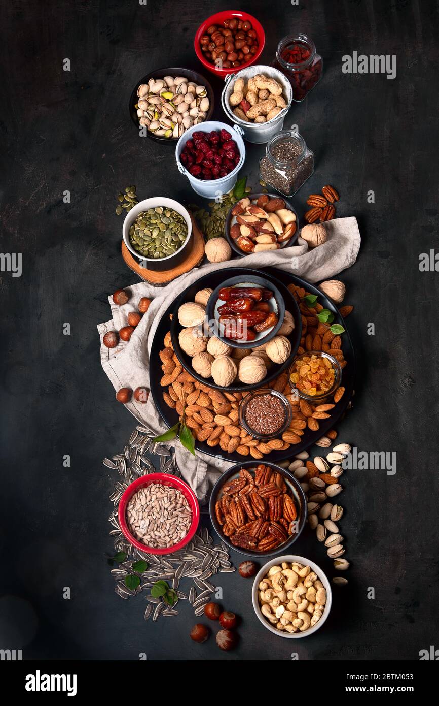 Different types of nuts, seeds and dried fruits on black background