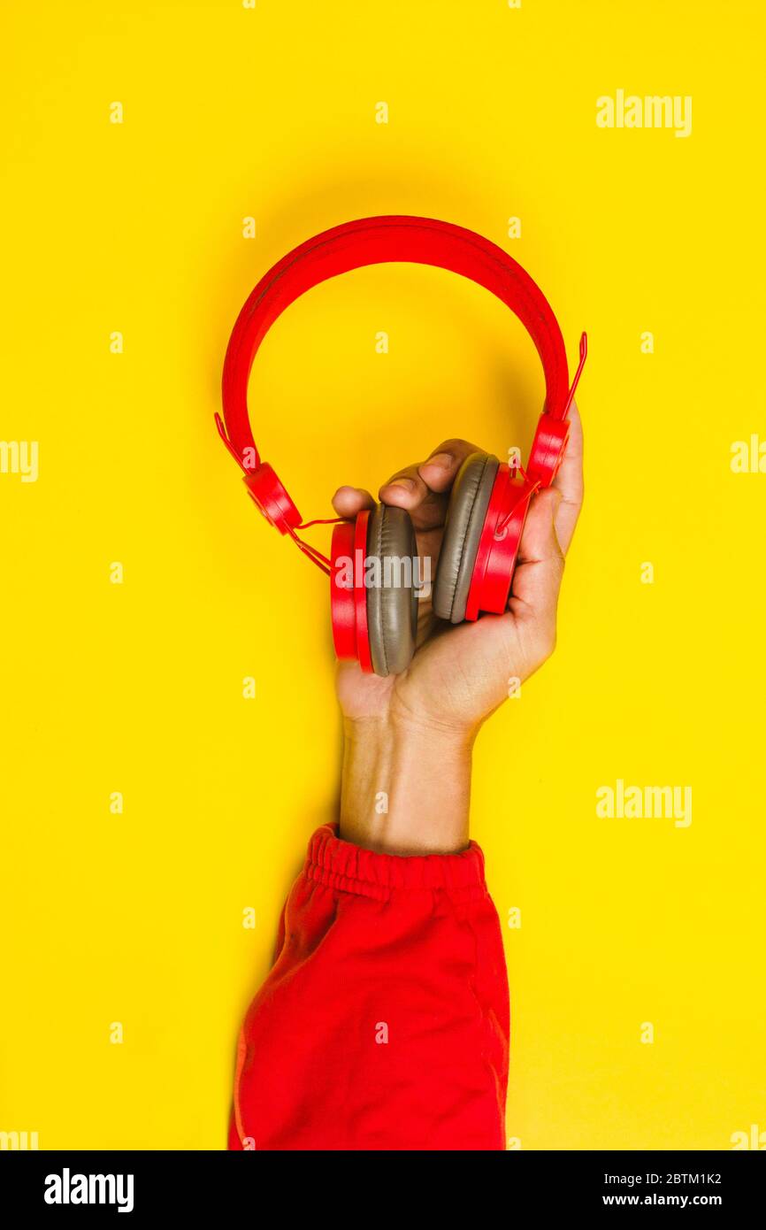 hand holding Red headphones on yellow background. Music concept Stock Photo