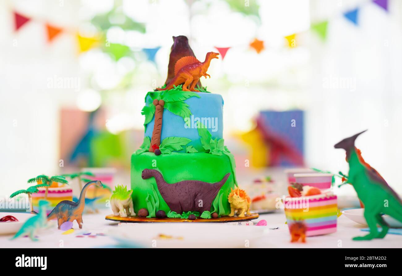 Kids birthday party. Dinosaur theme layer cake. Children event. Decoration for dinosaurs themed celebration. Stock Photo