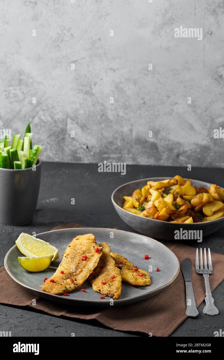 Fried breaded hake fillet with spice and roasted potato wedges Stock