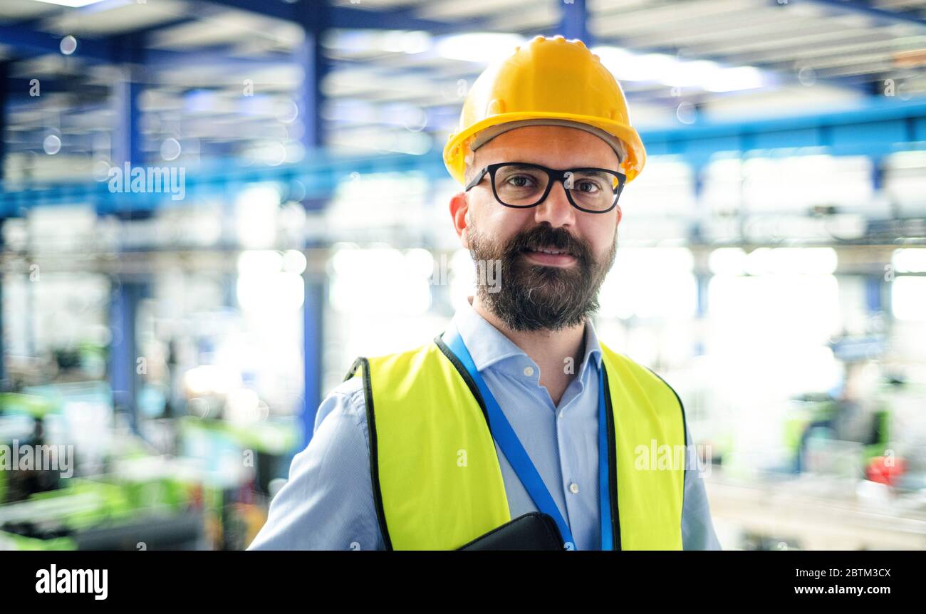 Front view of technician or engineer with hard hat standing in industrial factory Stock Photo