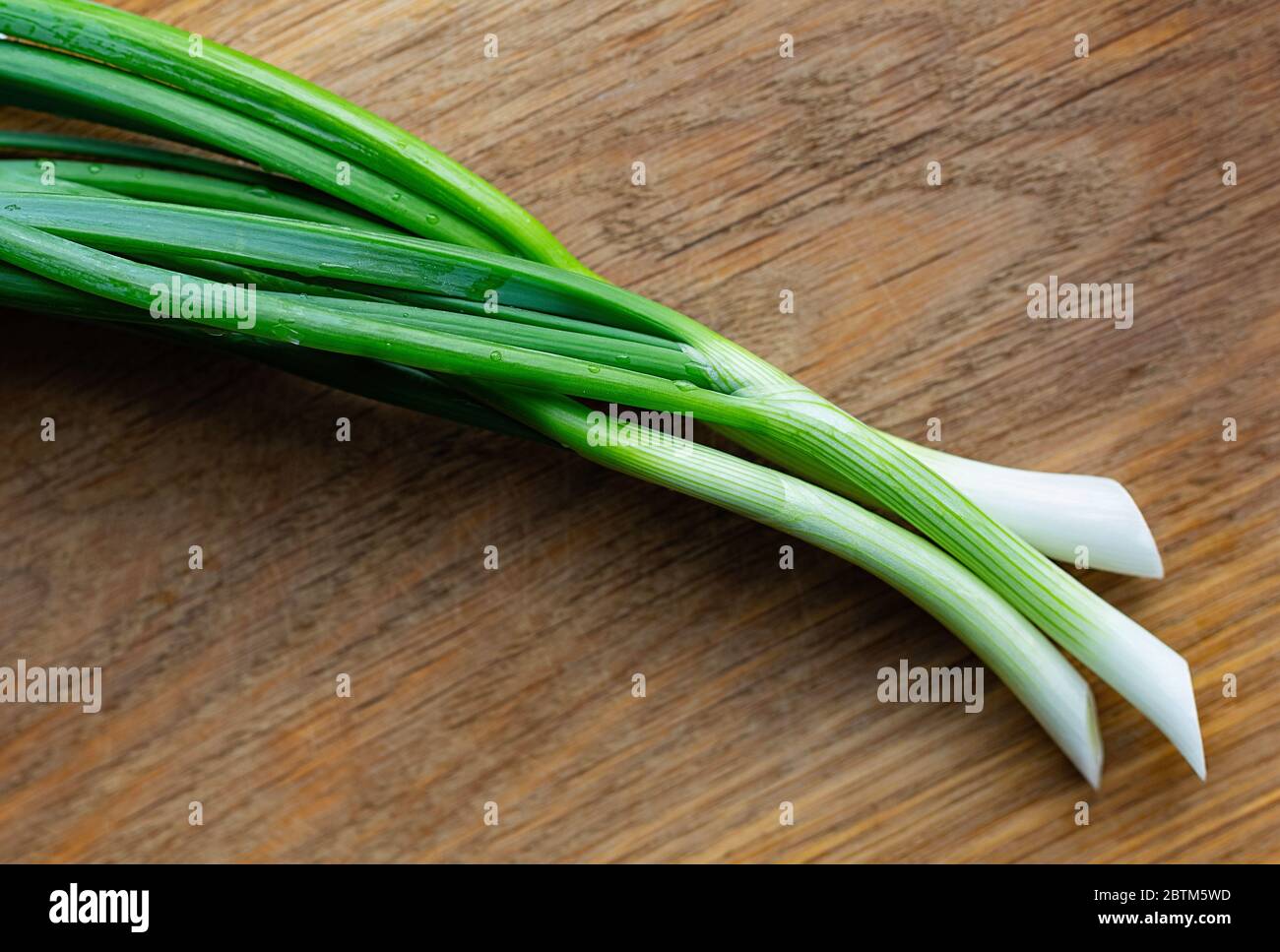 Young green onions on a wooden background. Food and health concept. Copy space. Stock Photo