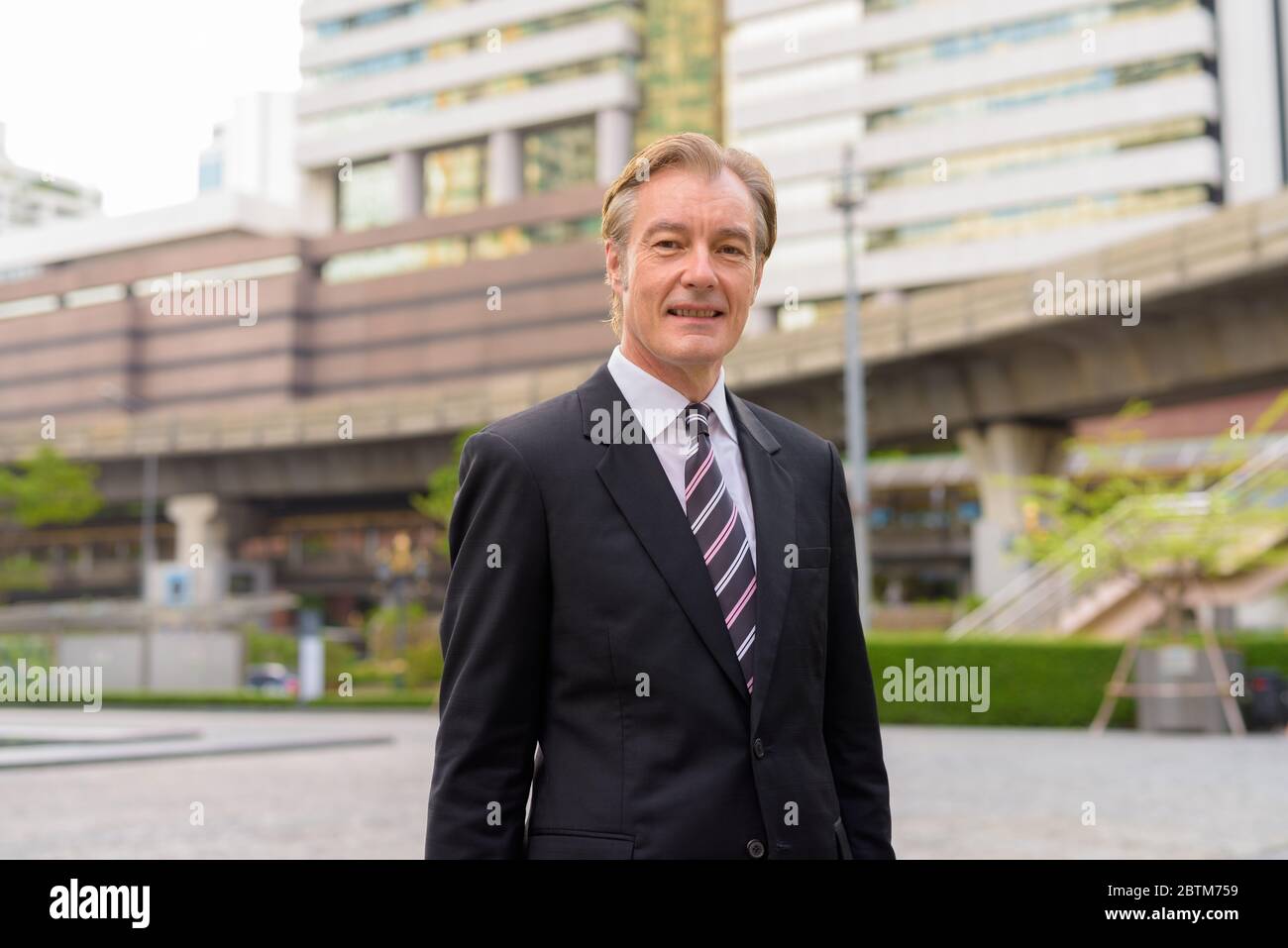 Happy mature handsome businessman smiling in the city outdoors Stock ...