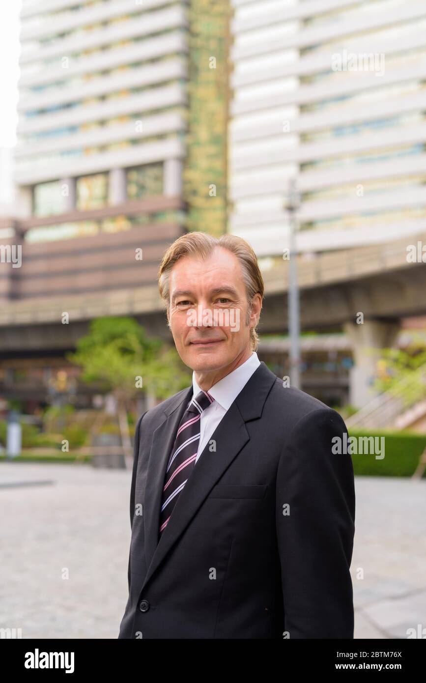 Mature handsome businessman wearing suit in the city outdoors Stock ...
