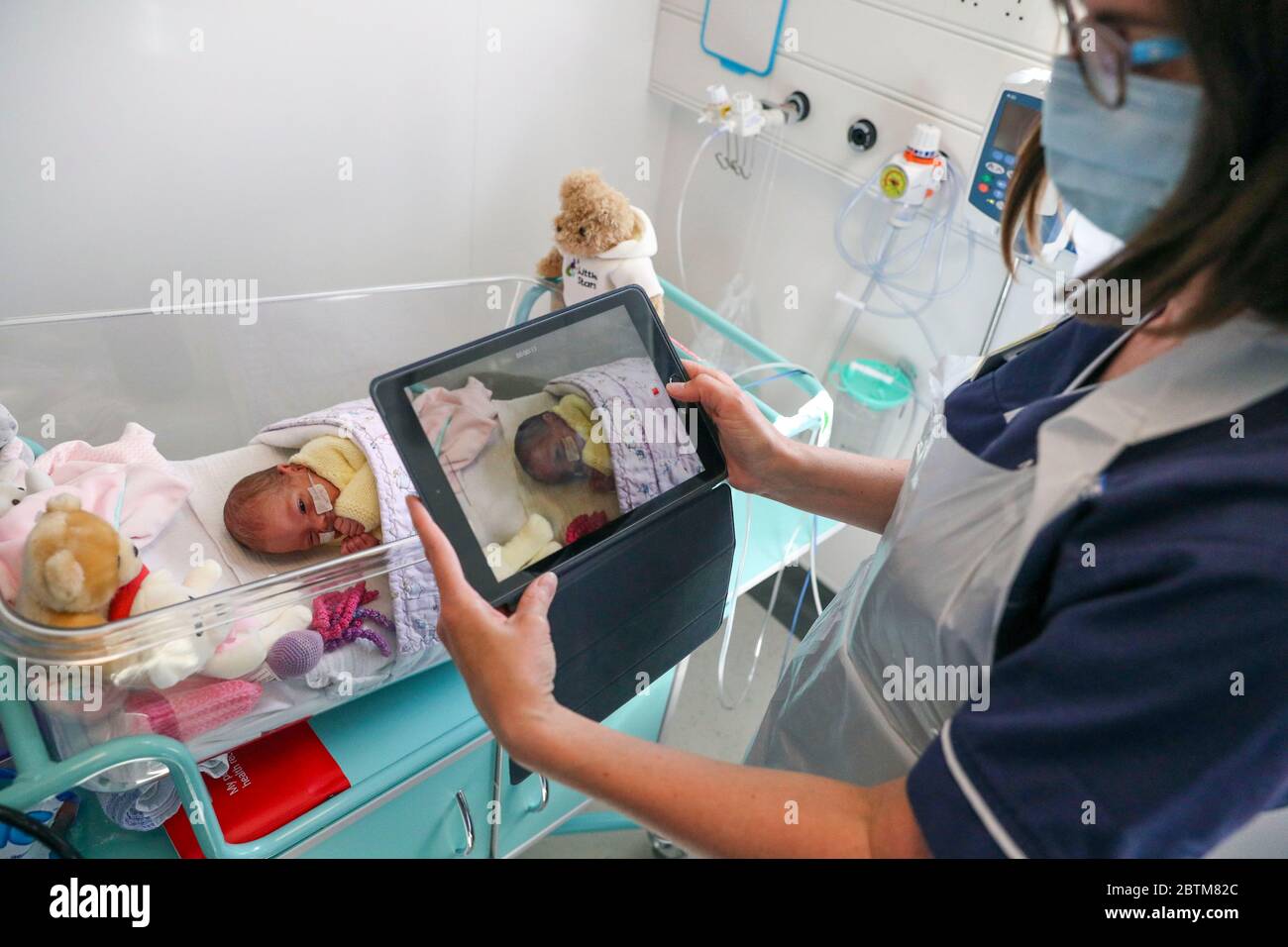 A nurse makes a video of a newborn baby in the maternity ward at Frimley Park Hospital in Surrey to send to the parents as visiting hours are restricted because of COVID pandemic. Picture date: 22/5/2020. Stock Photo