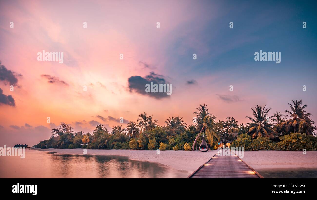 Beautiful sunset beach scene. Colorful sky and clouds view with calm sea and relaxing tropical mood Stock Photo