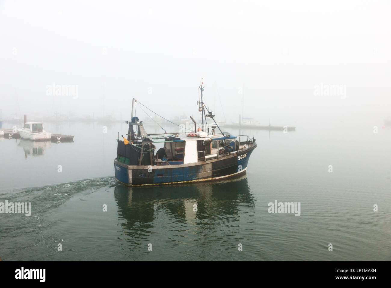 Crosshaven, Cork, Ireland. 27th May, 2020. Fishing boat Majestic IV slips away in early morning fog, as she heads for the fishing ground to check her pots for Crab in Crosshaven, Co. Cork, Ireland. Weather forcast for the day is that coastal fog will clear and become sunny everywhere with tempertures ranging between 20 to 24 degrees celcius.  - Credit; David Creedon / Alamy Live News Stock Photo