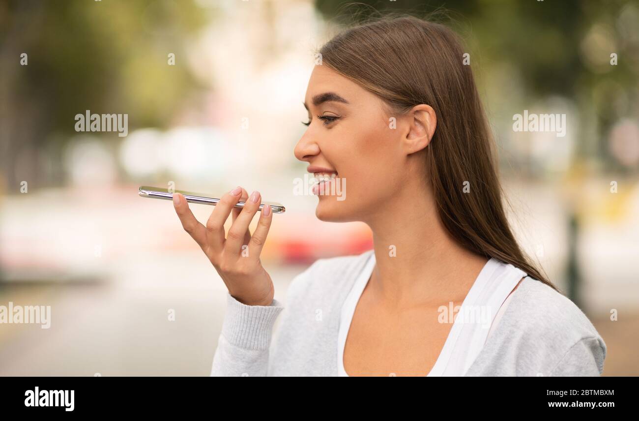 Smiling Girl Using Smartphone Voice Assistant Walking In Park Outdoors Stock Photo