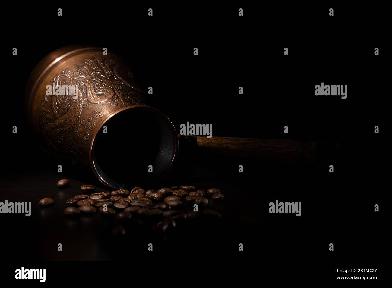 Oriental coffee maker with coffee beans on a black background. Stock Photo