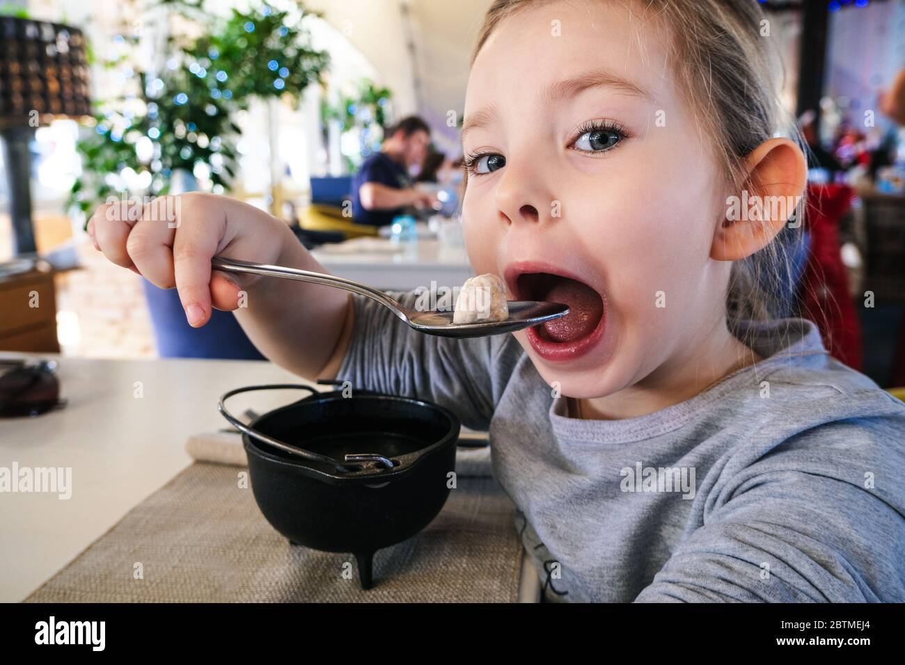 little girl eating dumpling in cafe Stock Photo