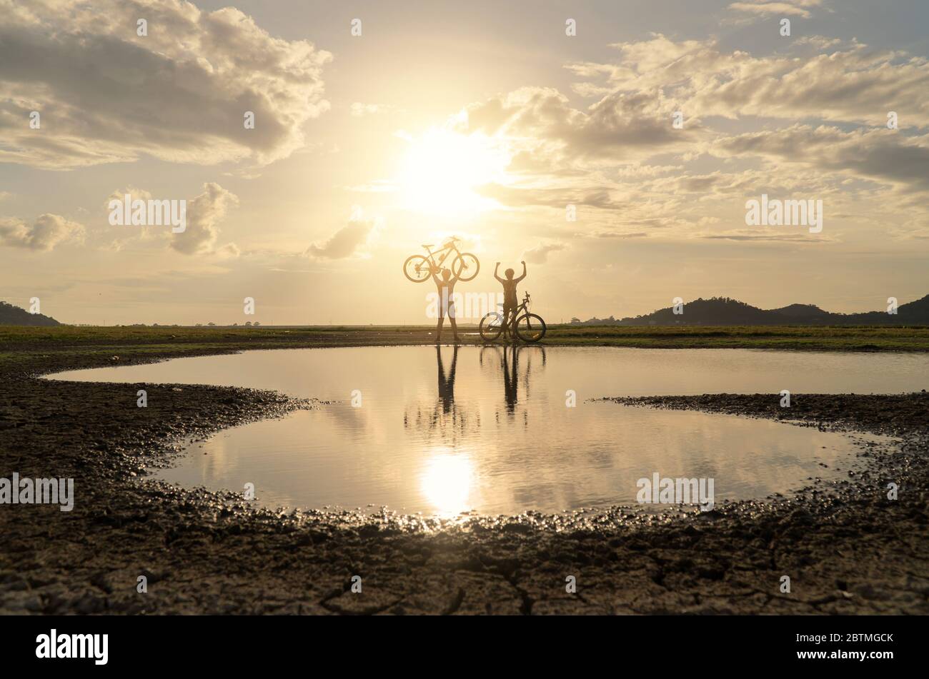 Young Couple in love fun and happy riding mountain bike after covid-19 coronavirus outbreak. End of the coronavirus outbreak. Silhouette cycling man a Stock Photo