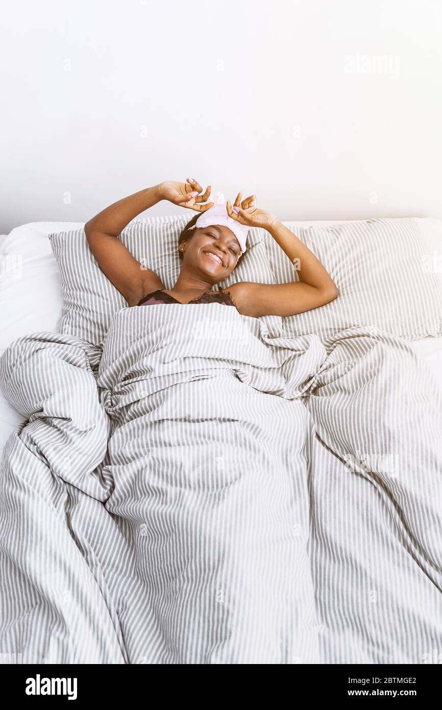 Smiling african american girl in sleep mask woke up in bedroom Stock Photo