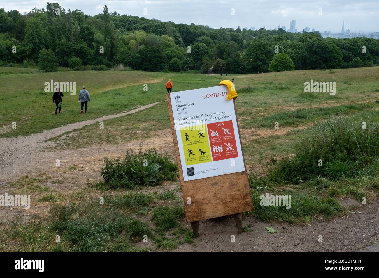 A sign on Hampstead Heath in North London warns visitors to keep their distance when walking because of the covid-19 pandemic. Stock Photo