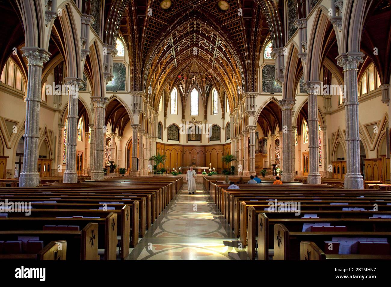 Horizontal view of the catholic Holy Name Cathedral interior with the priest walking along the central aisle, Chicago, Illinois, USA Stock Photo