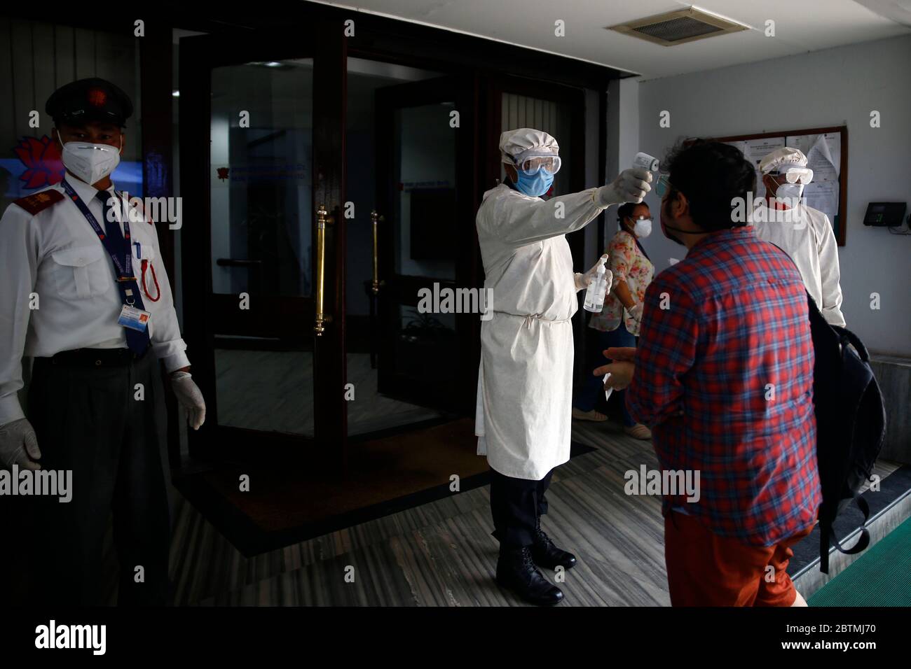 Kathmandu, Nepal. 27th May, 2020. A staffer checks temperature and sanitizes people entering the bank for safety measures amid concerns over the spread of coronavirus disease during the government imposed lockdown at Nepal Investment Bank head office in Kathmandu, Nepal on Wednesday, May 27, 2020. Credit: Skanda Gautam/ZUMA Wire/Alamy Live News Stock Photo