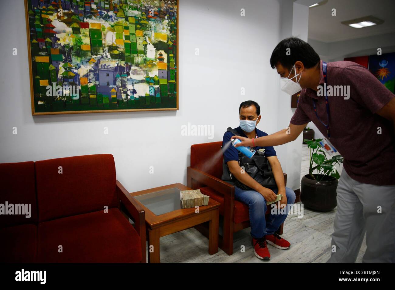 Kathmandu, Nepal. 27th May, 2020. A bank staffer disinfects notes for safety measures amid concerns over the spread of coronavirus disease during the government imposed lockdown at Nepal Investment Bank head office in Kathmandu, Nepal on Wednesday, May 27, 2020. Credit: Skanda Gautam/ZUMA Wire/Alamy Live News Stock Photo