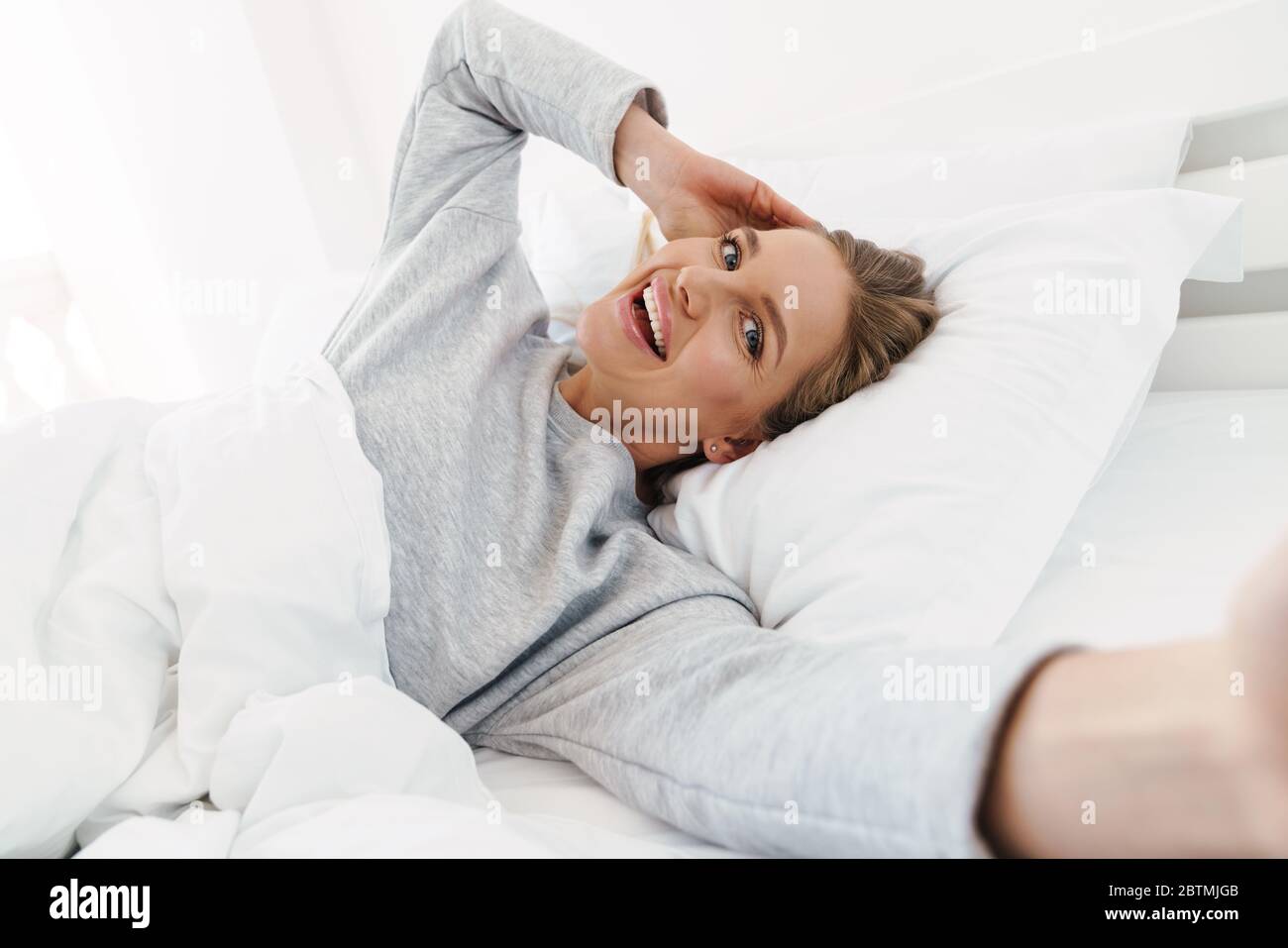 Image of cute cheerful woman smiling and taking selfie photo while ...