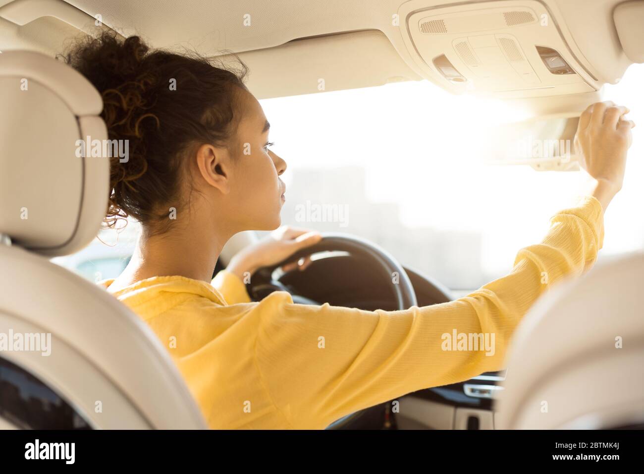African Woman Adjusting Mirrors Checking Auto During Test Drive, Back