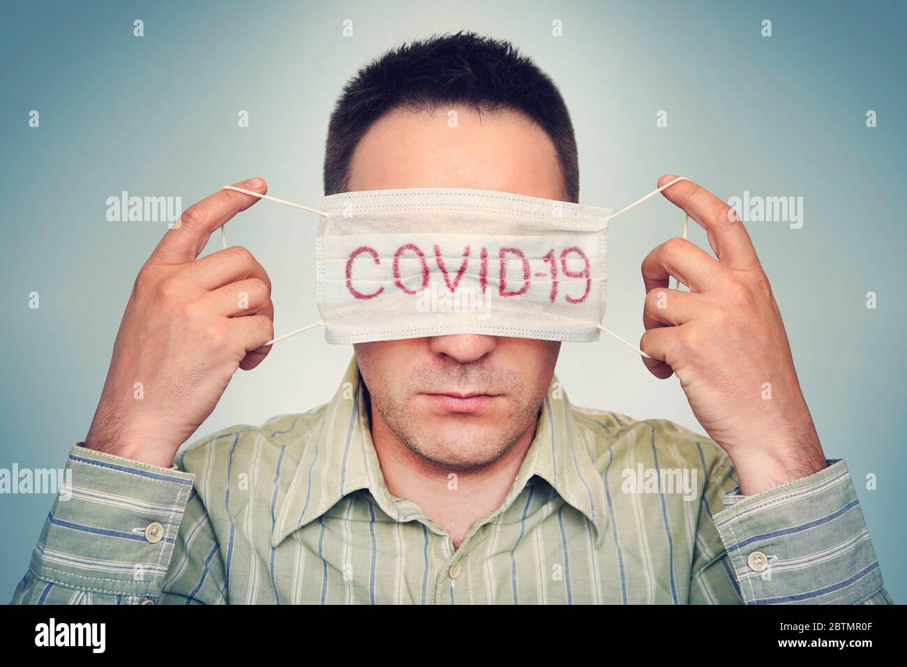 The man hides his eyes behind a medical mask marked Corvette. The concept of fatigue from global quarantine and self-isolation. Wearing face mask Stock Photo