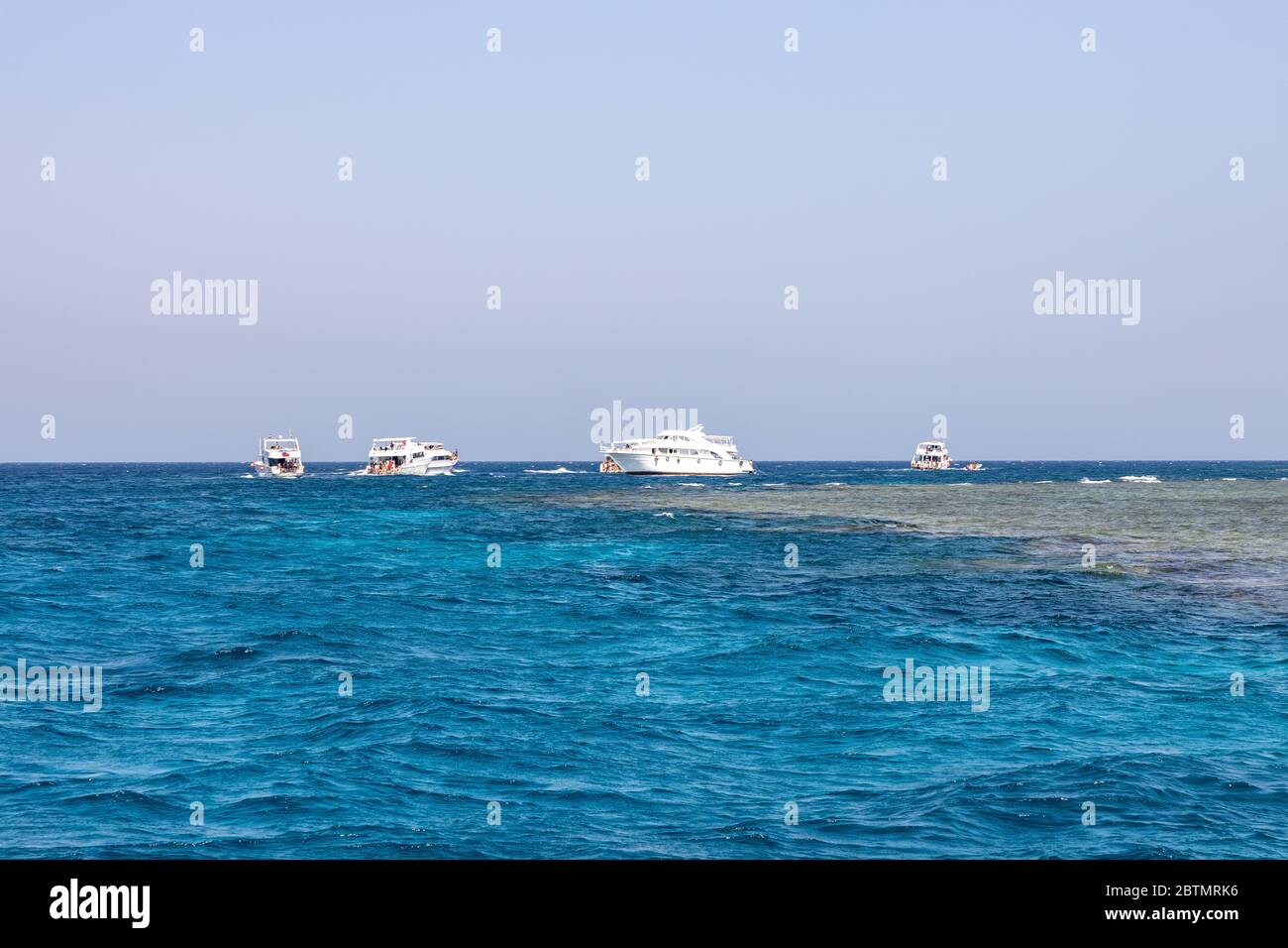 tourists boat near multicolored corrals. Corral reefs over water in Jaz 'ir Jift n, egypt Stock Photo