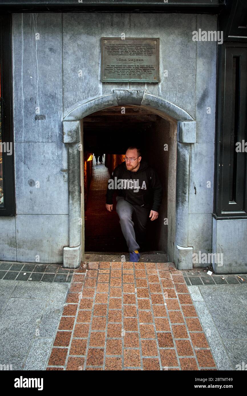 Wexford, Ireland - 10/30/2018: Man in UCLA shirt exits short archway from the 16th Century Keyser’s Lane on South Main St. in Wexford Ireland. Stock Photo