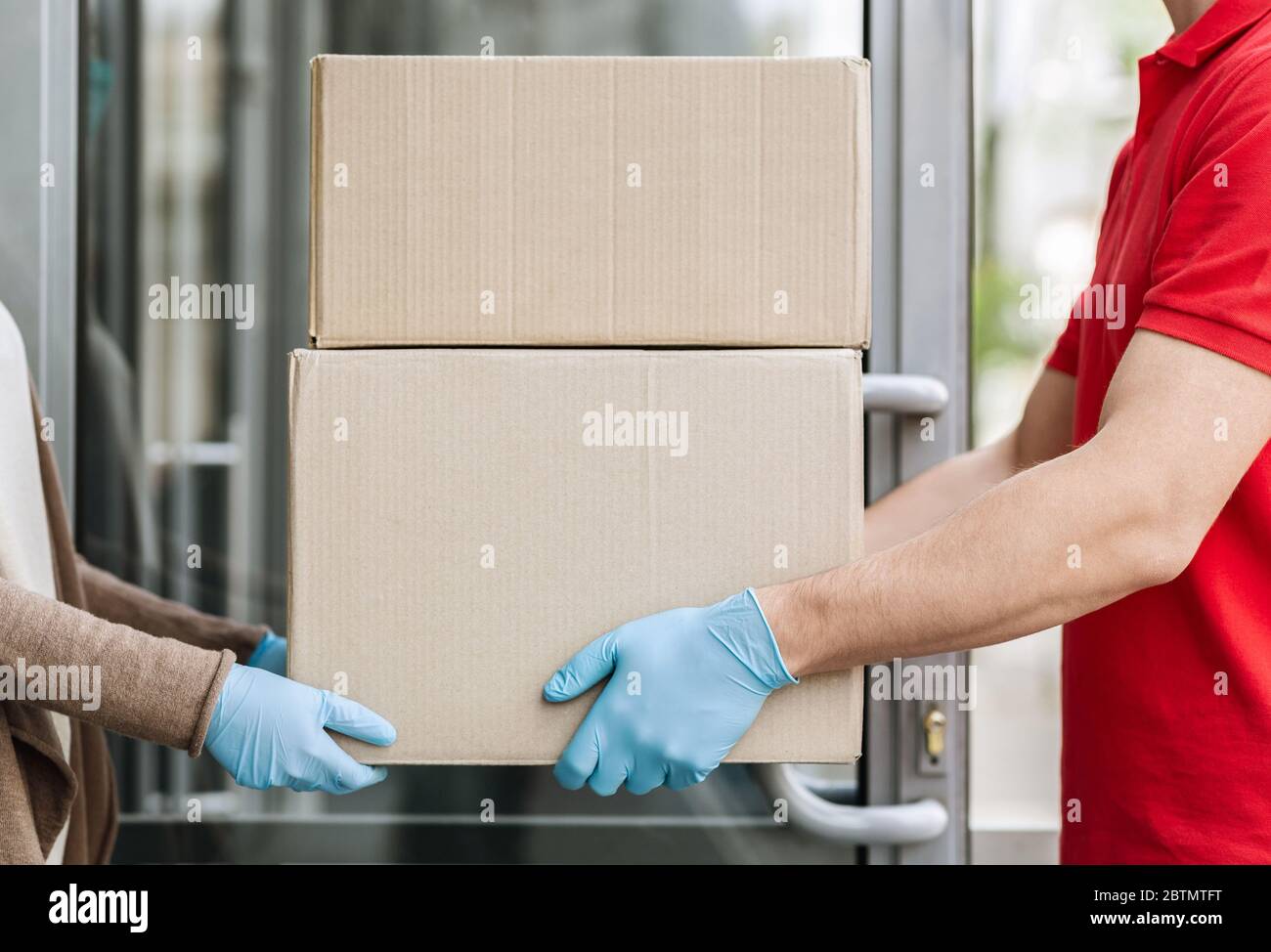 Online shopping and delivery to door concept. Courier delivers parcel to house during pandemic Stock Photo
