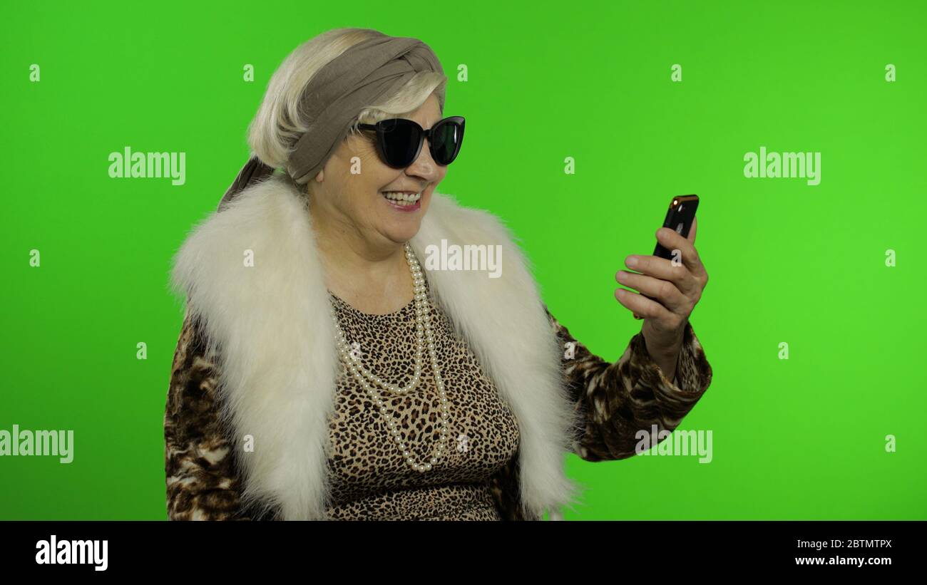 Elderly stylish granny caucasian mature woman using app on smartphone for  online shopping confused face expression. Chroma key background. Old  grandmother in fashion wearing browsing on mobile phone Stock Photo - Alamy