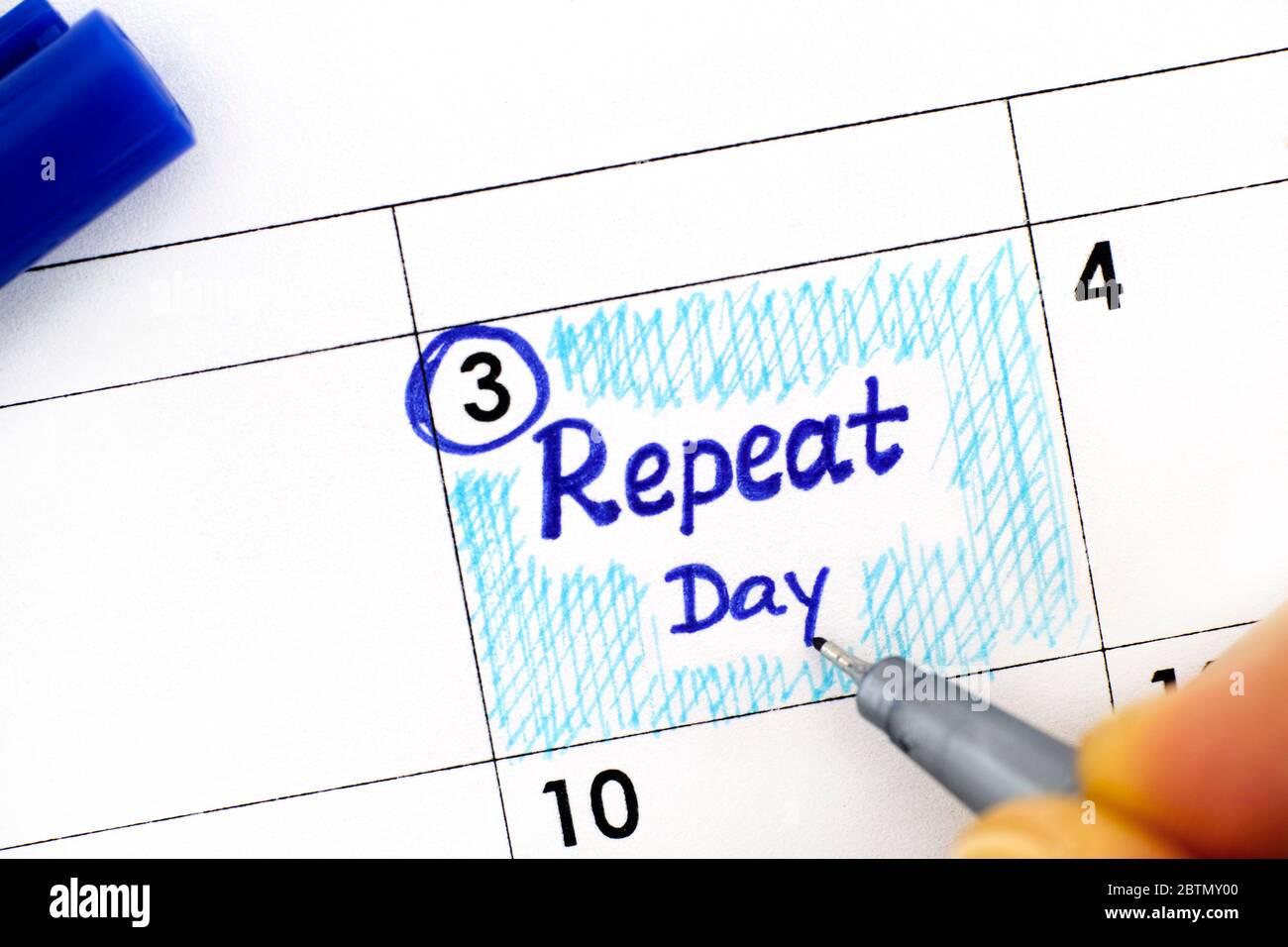 Woman fingers with pen writing reminder Repeat Day in calendar. June 03. Stock Photo