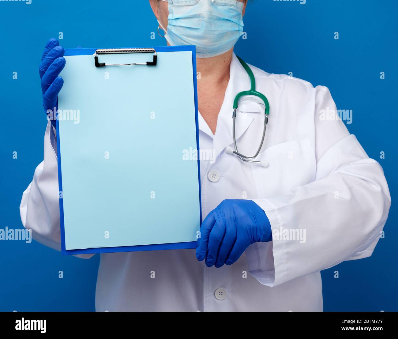 female doctor dressed in a white medical gown and blue latex gloves ...