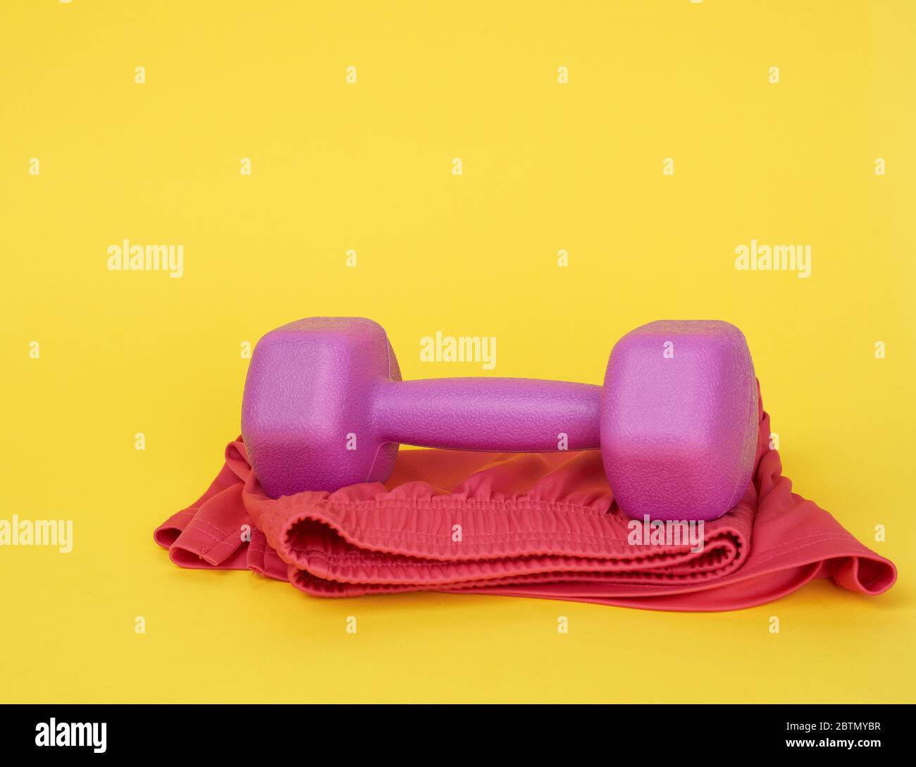 pink plastic dumbbells of one kilogram on a yellow background, sports ...