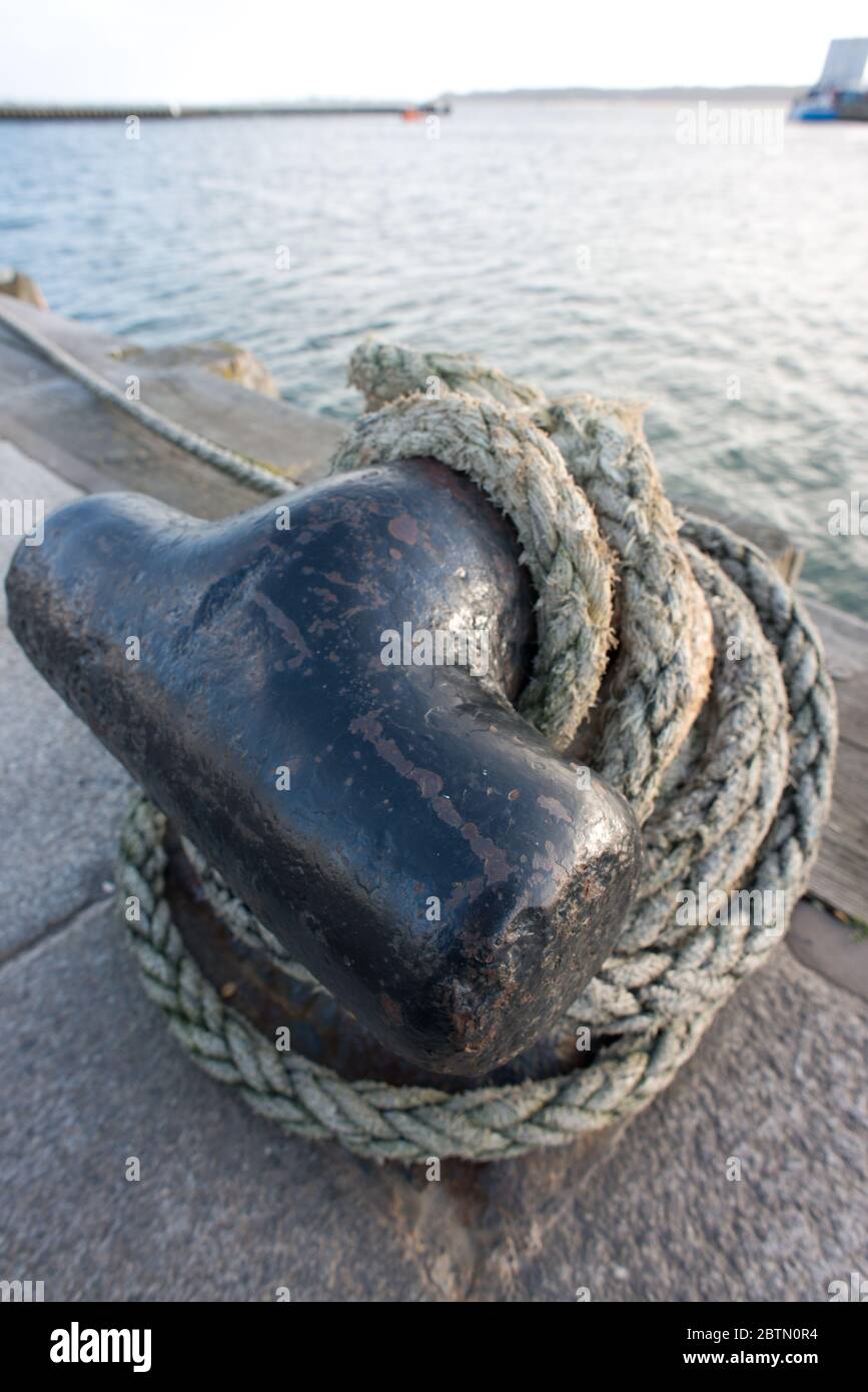 close-up of a quayside mooring bollard with thick rope tied around it Stock Photo