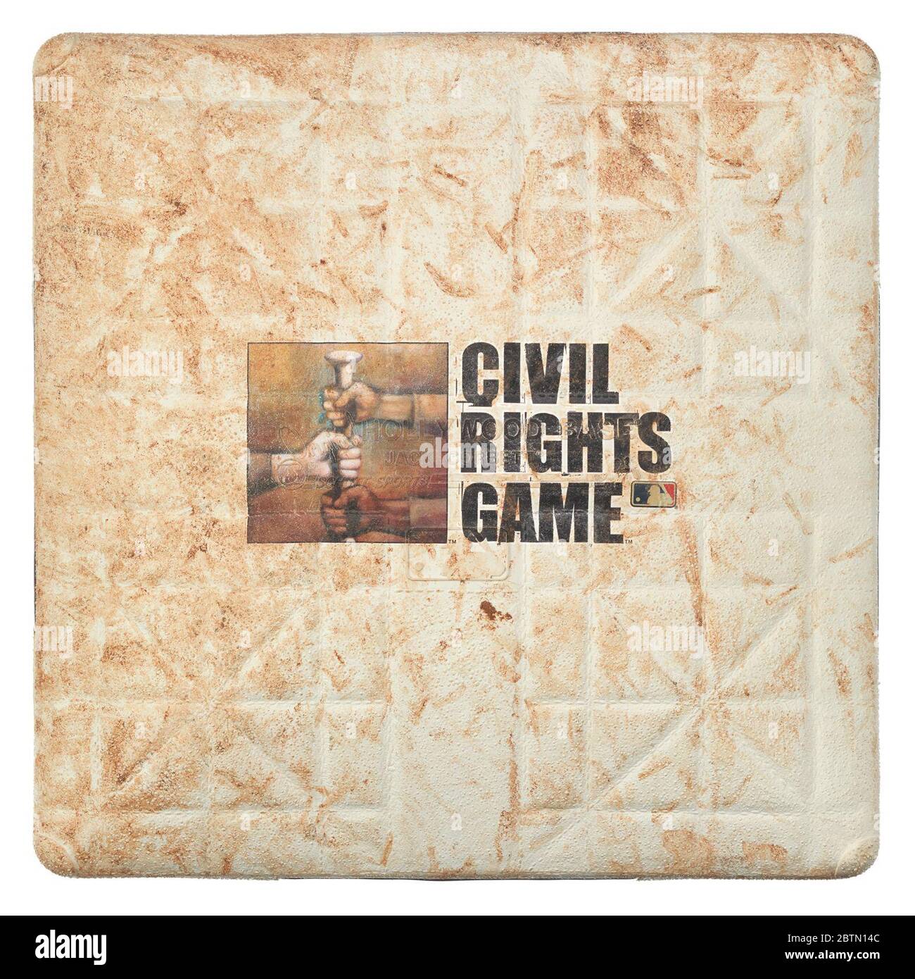 First base used in Inaugural Civil Rights Game. Square first base baseball base used in the 2007 inaugural Major League Baseball [MLB] Civil Rights baseball game. Top of base has printed design featuring an illustration of three fists grabbing a bat. Next to the design, black type reads, [CIVIL / RIGHTS / GAME]. Stock Photo
