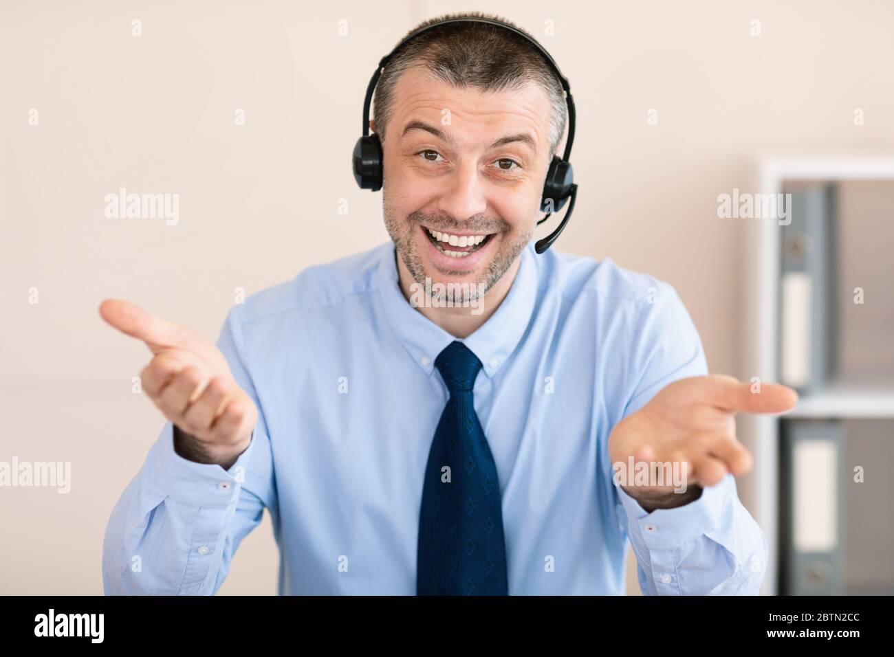 Man In Headset Smiling Sitting In Customer Support Office Stock Photo