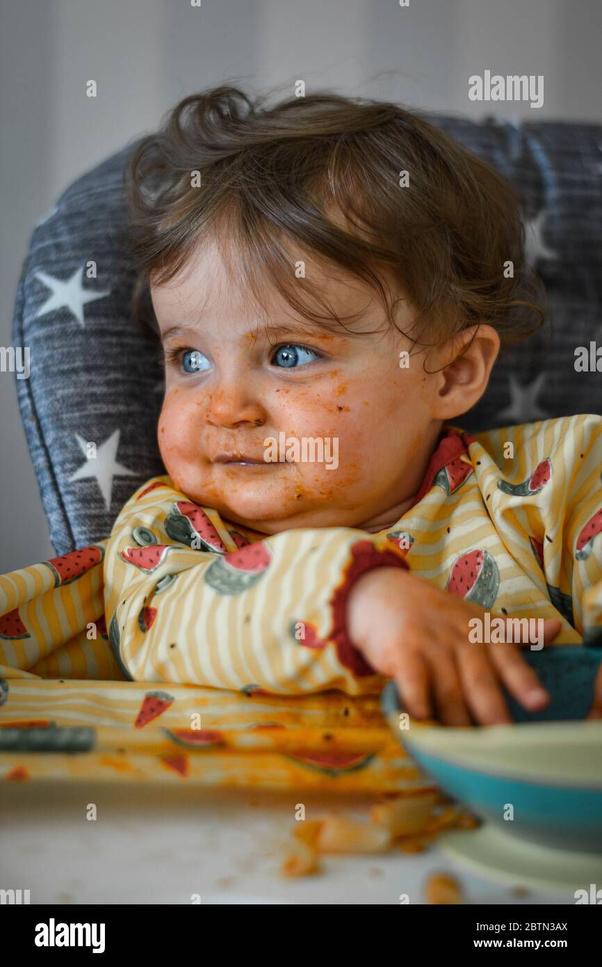 Baby eating food with a messy face Stock Photo