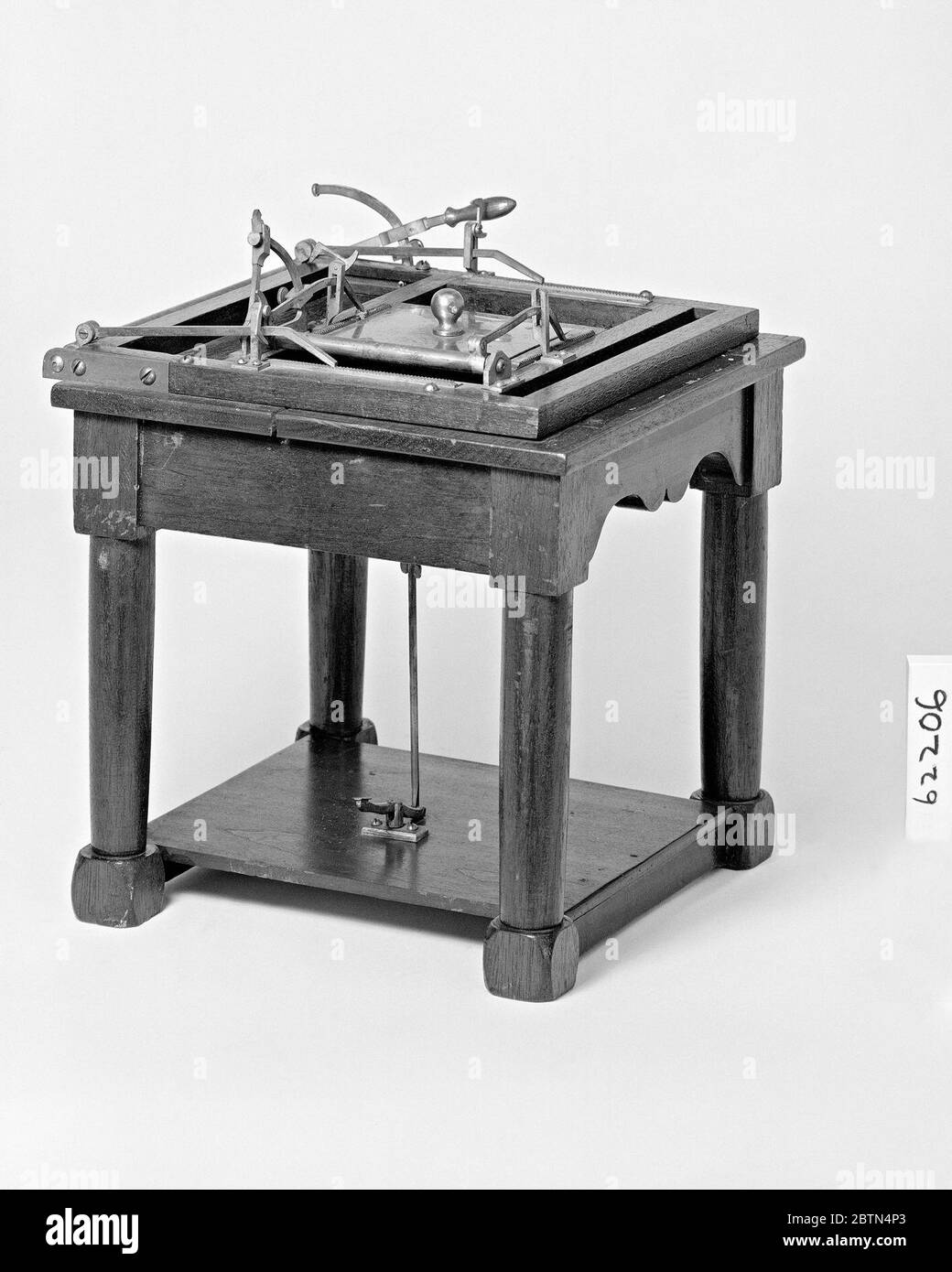 Patent Model of a Printing Apparatus for the Blind. This patent model demonstrates an invention for producing embossed letters on paper for communication between blind people; the invention was granted patent number 62206. Raised letters on plungers on a disk above the table were matched with sunken letter plungers below it. Stock Photo