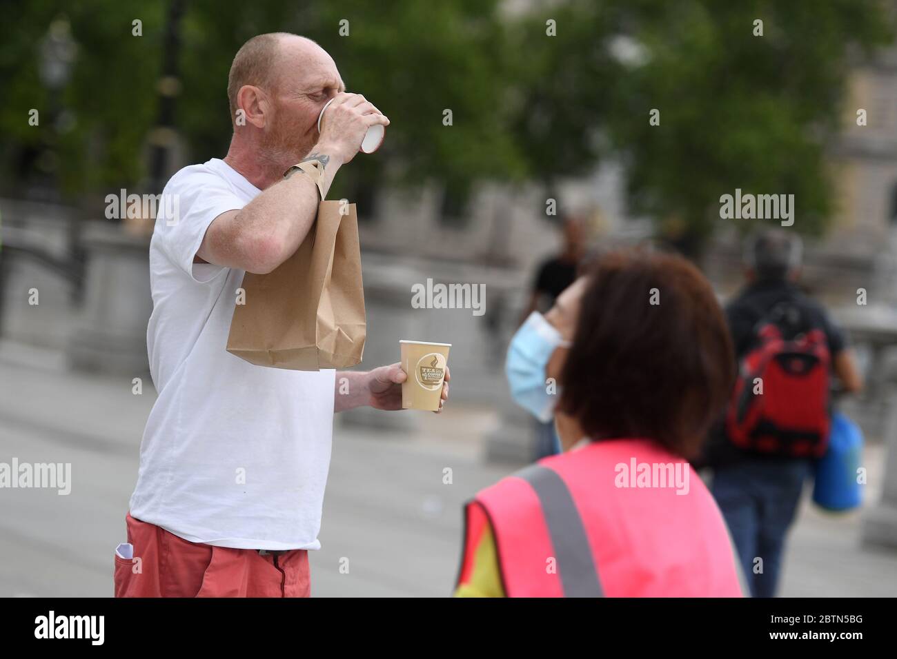 A man drinks his free coffee in Trafalgar Square, London, where Pandemic Pizza and Trafalgar Square Refreshment Hub have teamed up to to provide homeless people with refreshments, after the introduction of measures to bring the country out of lockdown. Stock Photo