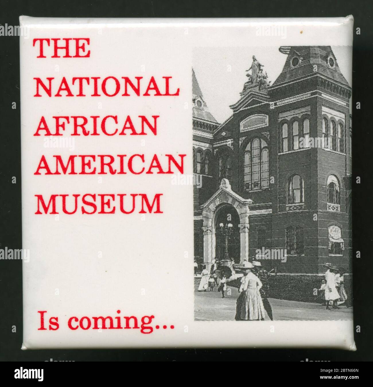 Pinback button promoting the arrival of the National African American Museum. Square pin-back button featuring a black and white image of the Smithsonian Arts and Industries building. To the left of the black and white photograph is red type that reads, [THE/NATIONAL/AFRICAN/AMERICAN/MUSEUM/Is coming…]. Stock Photo