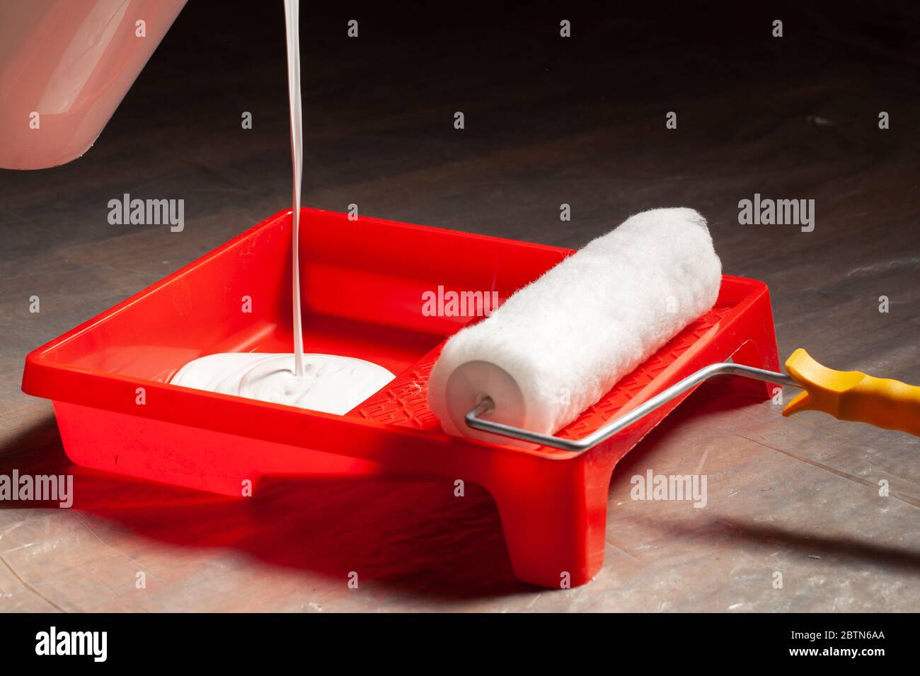 Pouring white latex paint in a tray before painting a room. Stock Photo