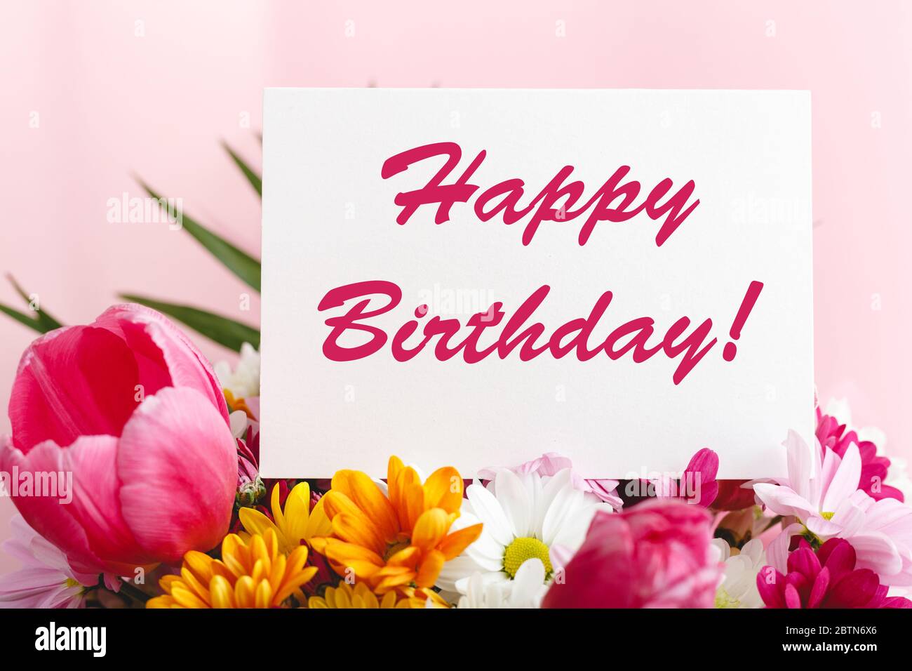 Happy birthday text on card in flower bouquet on pink background ...