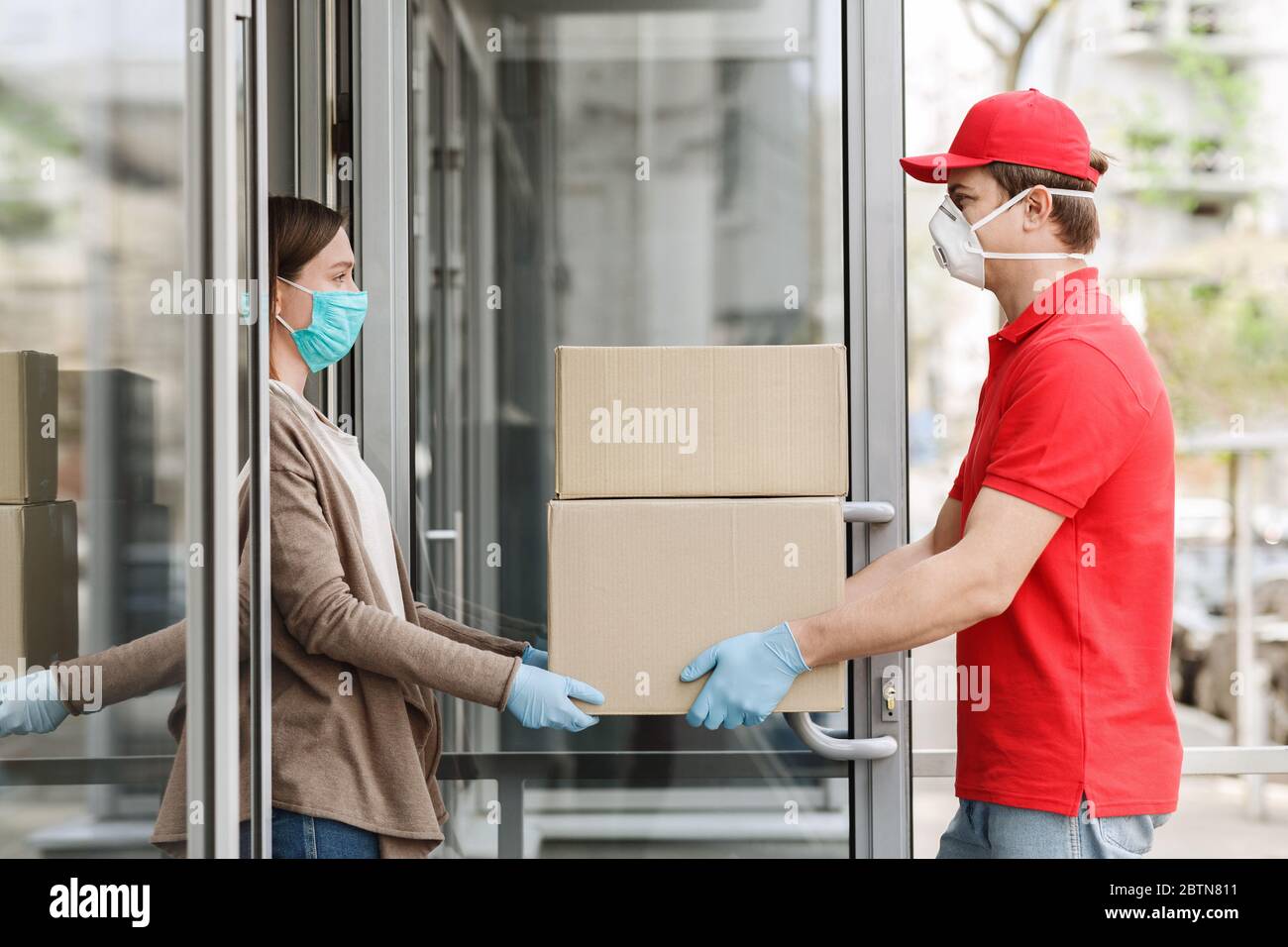 Protect clients from 2019-ncov. Courier delivers packages to girl at home Stock Photo