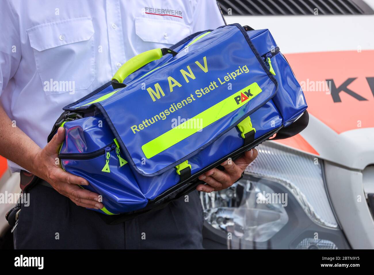 27 May 2020, Saxony, Leipzig: A firefighter holds a special bag for  so-called mass casualty and illness incidents (MANV) in front of an  ambulance. Inside the bag are, among other things, special