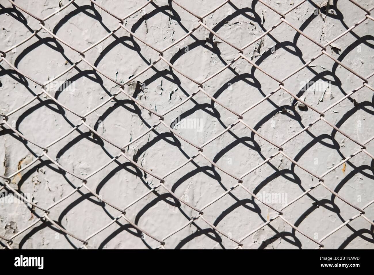 Metal mesh pattern on concrete wall background with shadow. Abstract texture Stock Photo
