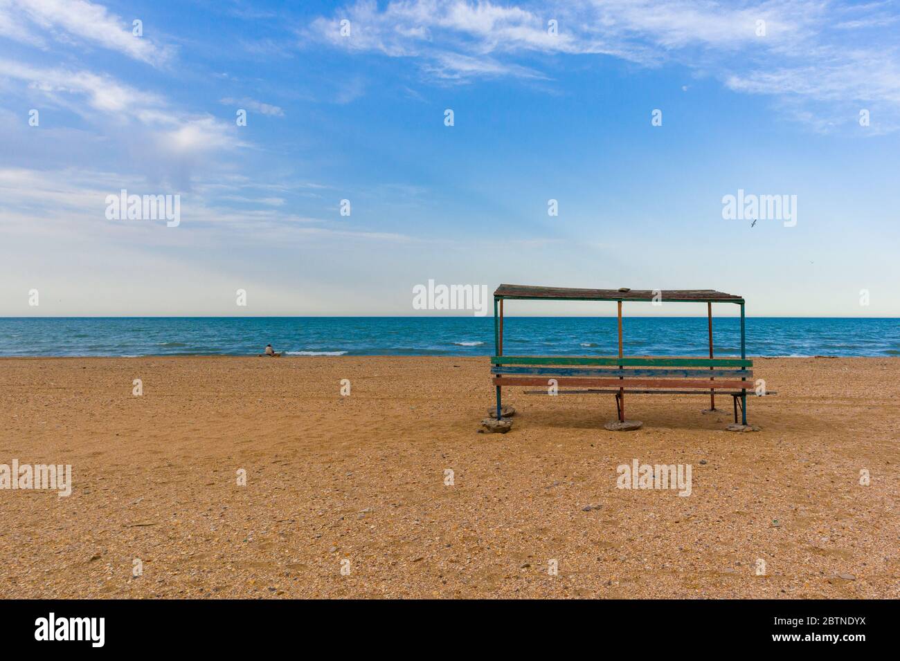 A large bench with a roof set on the beach with epic clouds. Landscape photo for background.  Stock Photo