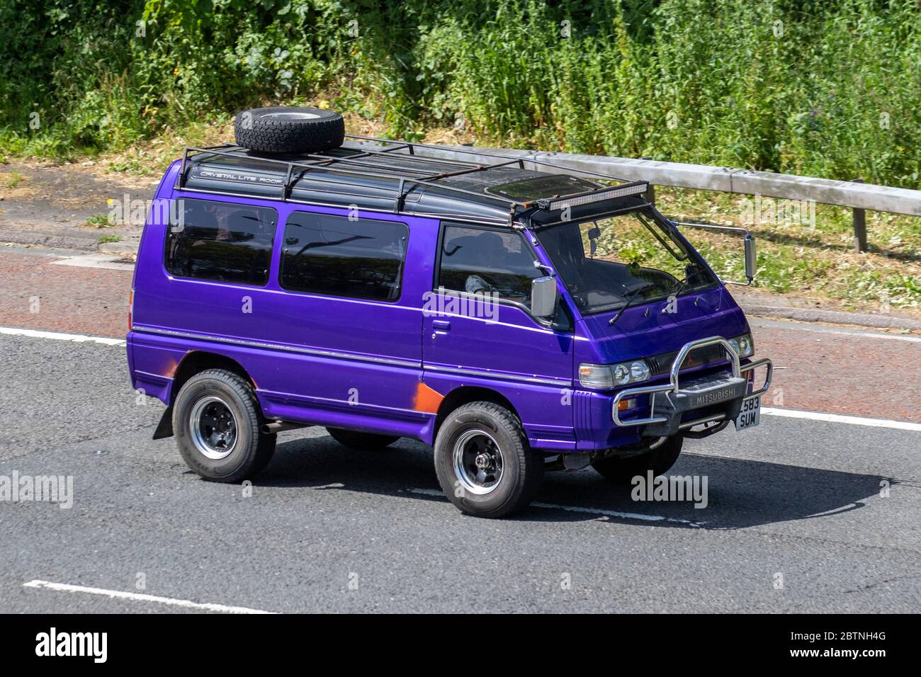 1994 90s nineties purple Mitsubishi Delica window van kombi with roof rack  and spare tyre; Vehicular traffic moving vehicles, cars vehicle, roads,  caravan, travel, camping, transport, kombi, vacation, camper motors  tourism, motorhome