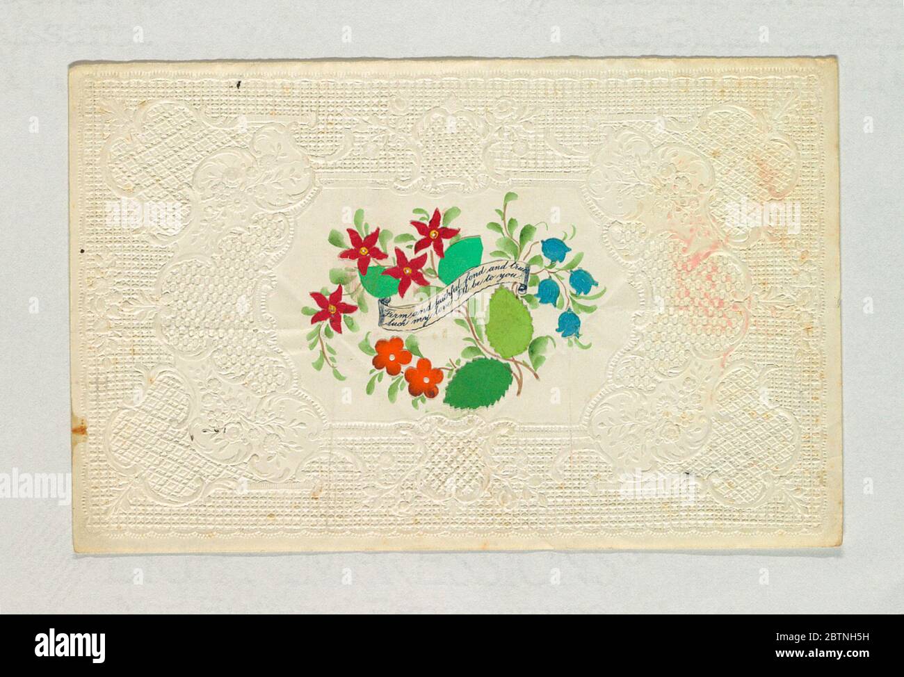 Valentine Greeting. Research in ProgressA bunch of flowers in an embossed paper enframement and in the center a printed inscriptional ribbon: 'Firm and faithful, fond and true / Such my love I'll be with you'. Stock Photo