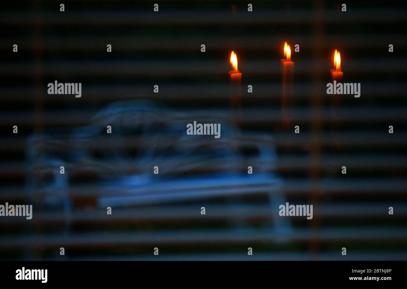 Candles reflected in a window looking onto a garden bench sitting in the back garden of a house in east Belfast, Northern Ireland. Stock Photo