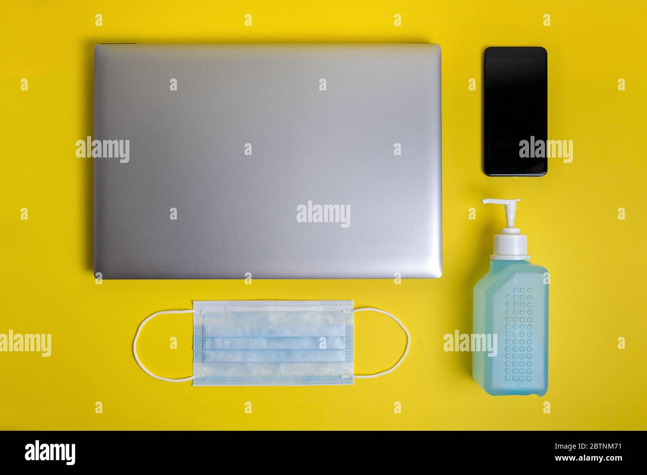Yellow Computer Mask Protection protective mask, disinfectant gel, computer and telephone on a yellow ...