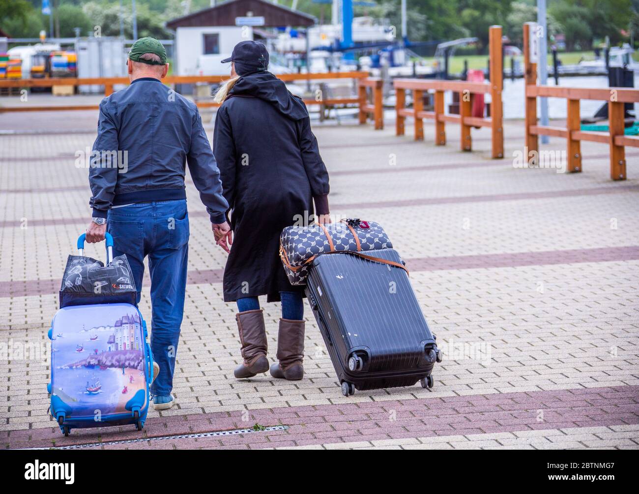 25 May 2020, Mecklenburg-Western Pomerania, Schaprode: The first holidaymakers return to the Baltic Sea after the Corona travel ban has been lifted. They pull out their suitcases in the port of Schaprode on Rügen to the ferry for the crossing to the Baltic Sea island of Hiddensee. Photo: Jens Büttner/dpa-Zentralbild/ZB Stock Photo
