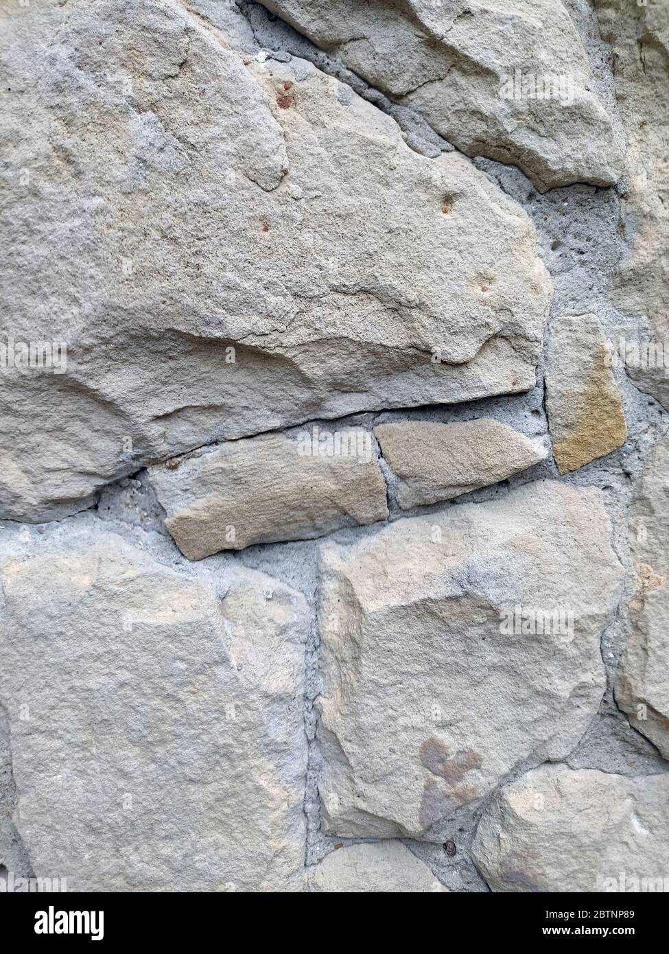 Gray stone wall background, mosaic stonewall rubble facade closeup